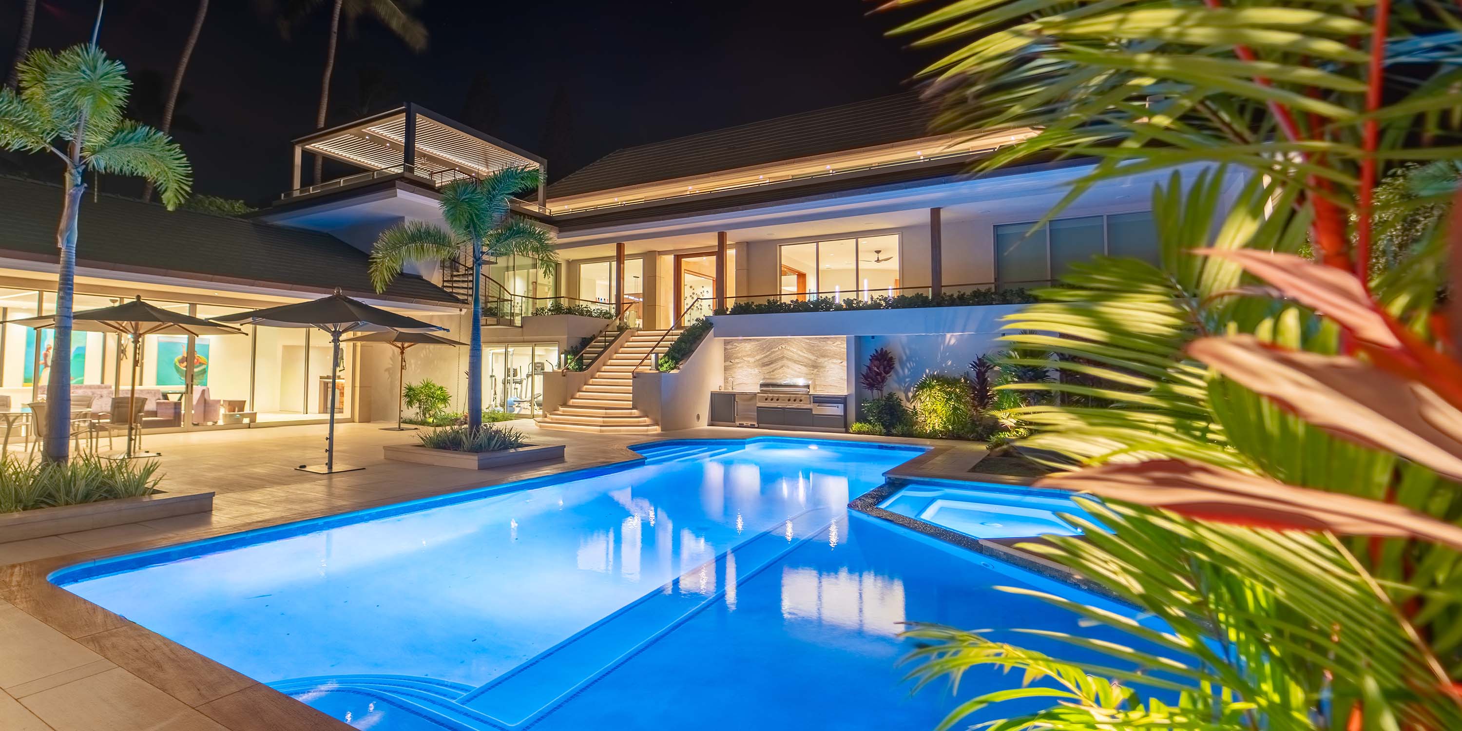 Modern two-story home with path lighting, smart lock, cameras, and a pool in view